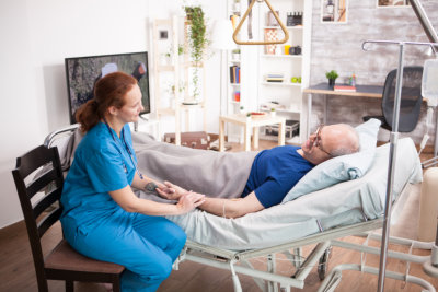 woman caregiver assisting the elderly man in bed